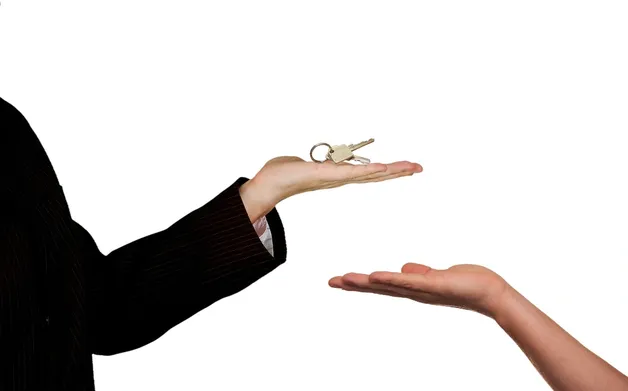 Schlüsselübergabe zwischen Maklerin und Kundin nach erfolgreichem Immobilienverkauf
